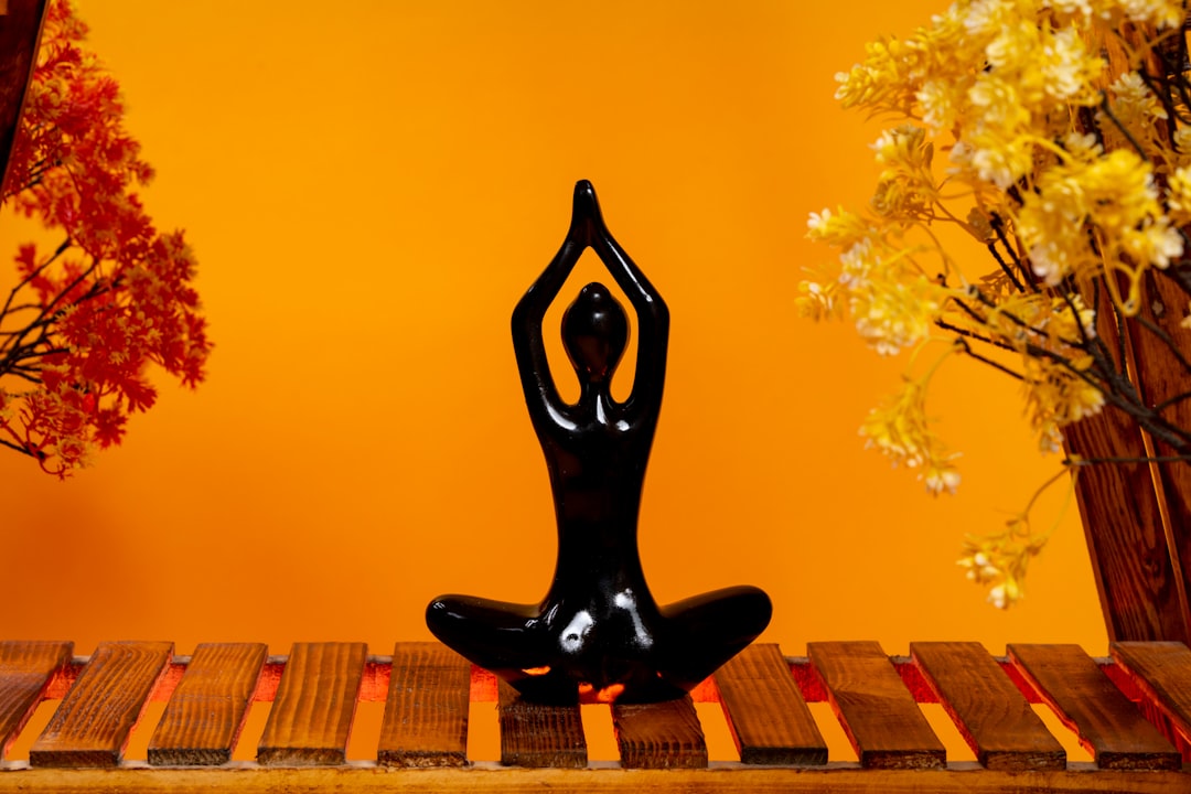 a-statue-of-a-person-doing-yoga-on-a-wooden-table-0wtgohi0swo